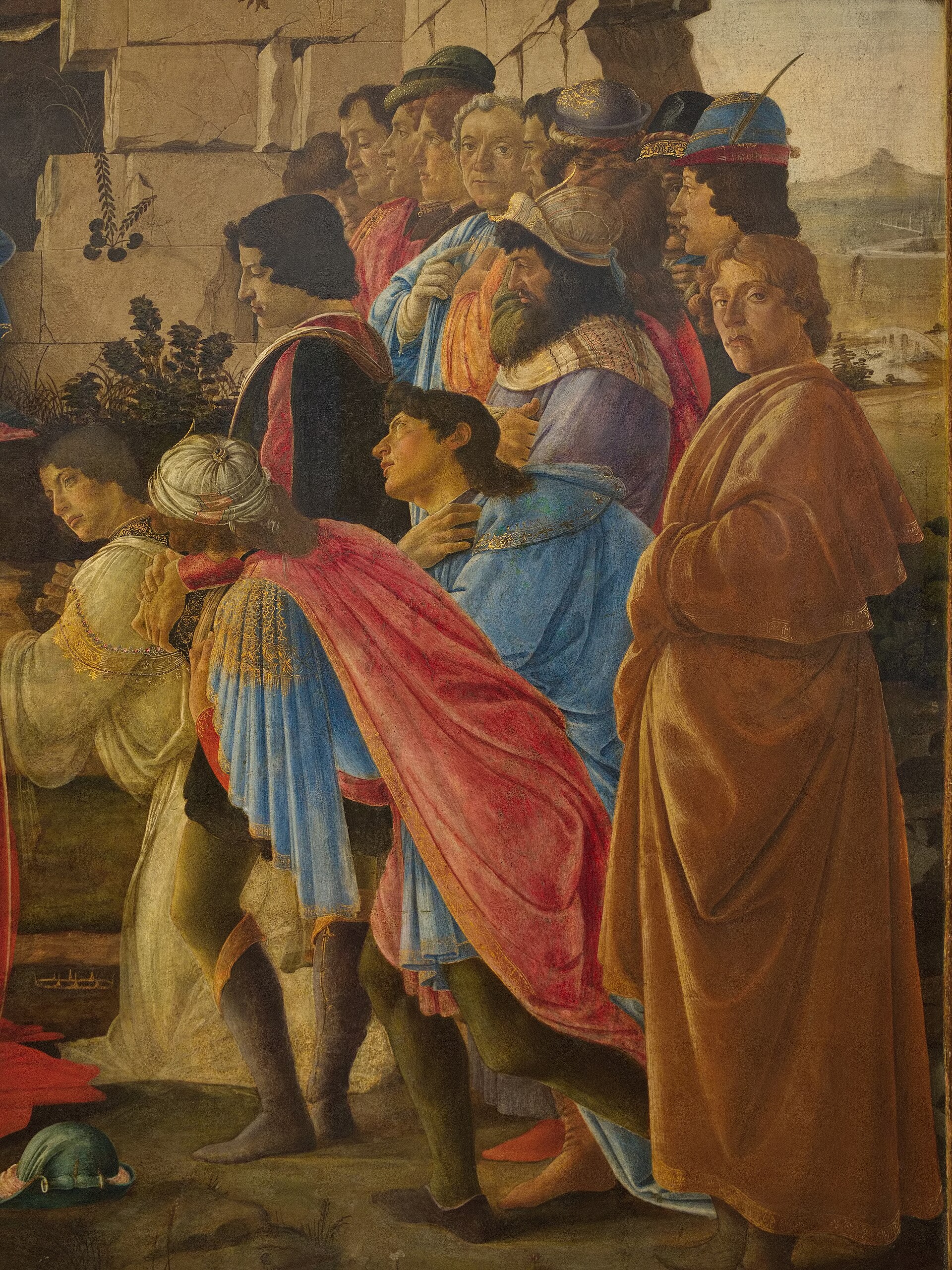 Detail of the figure at the far right of the painting: a young man in a blond beard and a yellow-gold cloak, looking directly out at the viewer, identified by Vasari as Botticelli's self-portrait.