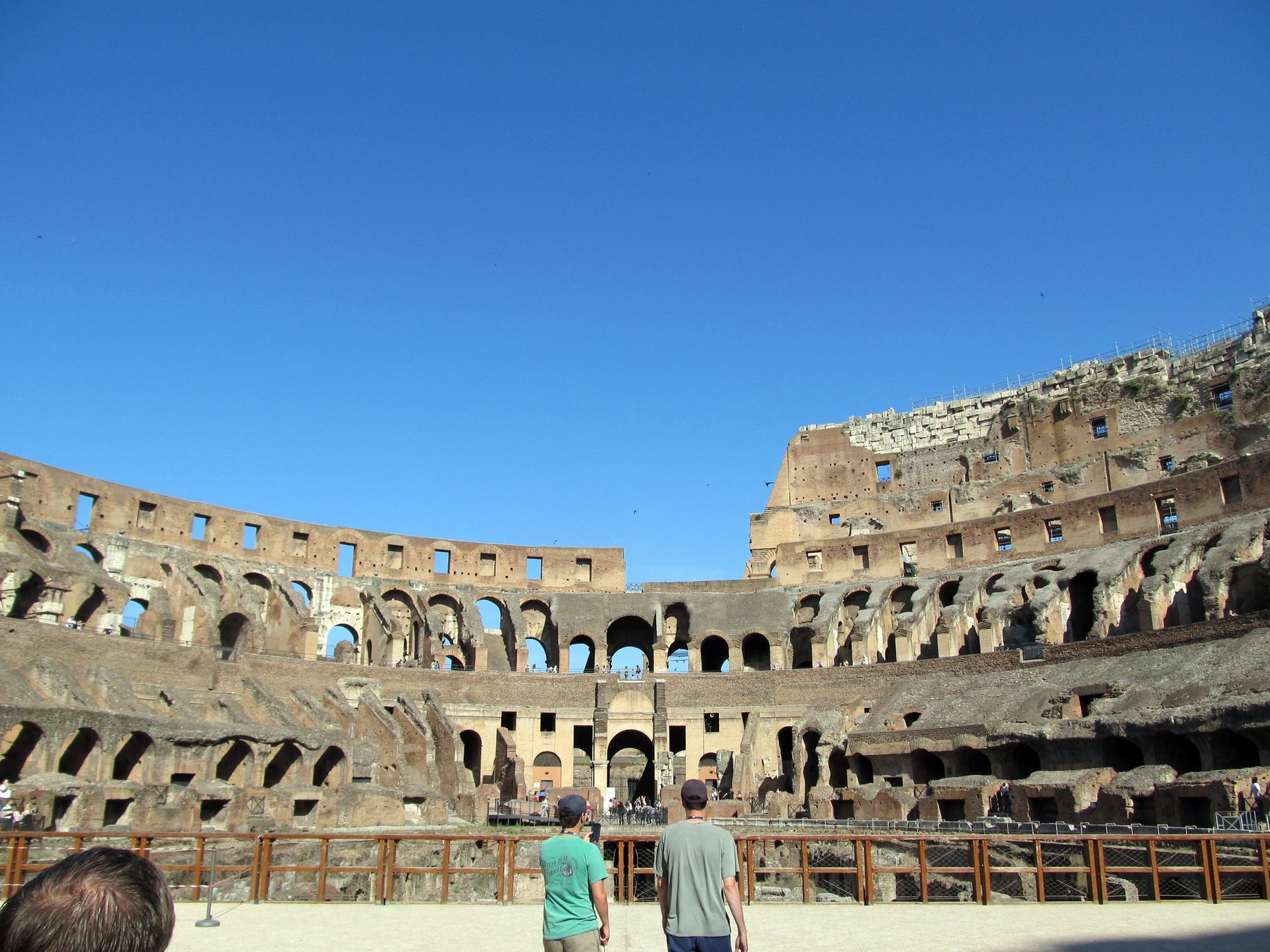 A view from inside the seating tiers of the Colosseum looking down at the partially reconstructed arena floor and the exposed brickwork of the hypogeum below.