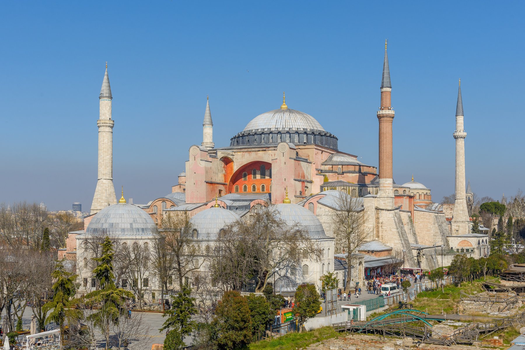The Hagia Sophia in Istanbul seen across the Bosphorus, its central dome flanked by four Ottoman minarets, set against a clear sky.