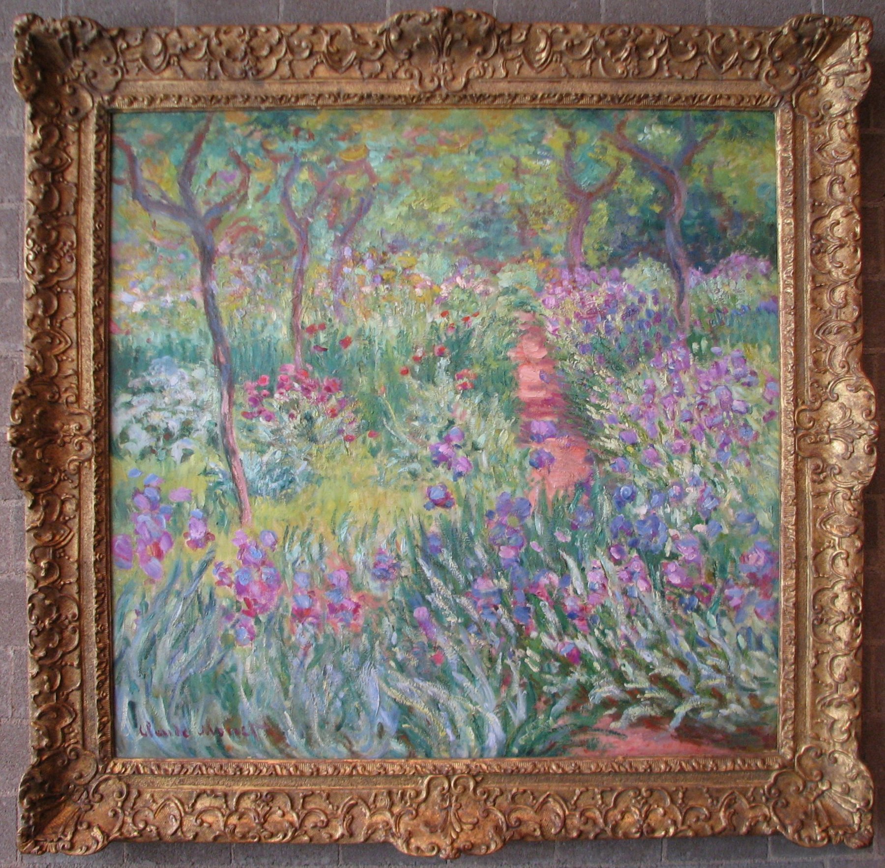 Claude Monet's The Artist's Garden at Giverny (1900), looking down the long path of irises in spring bloom toward the studio at the back of the property