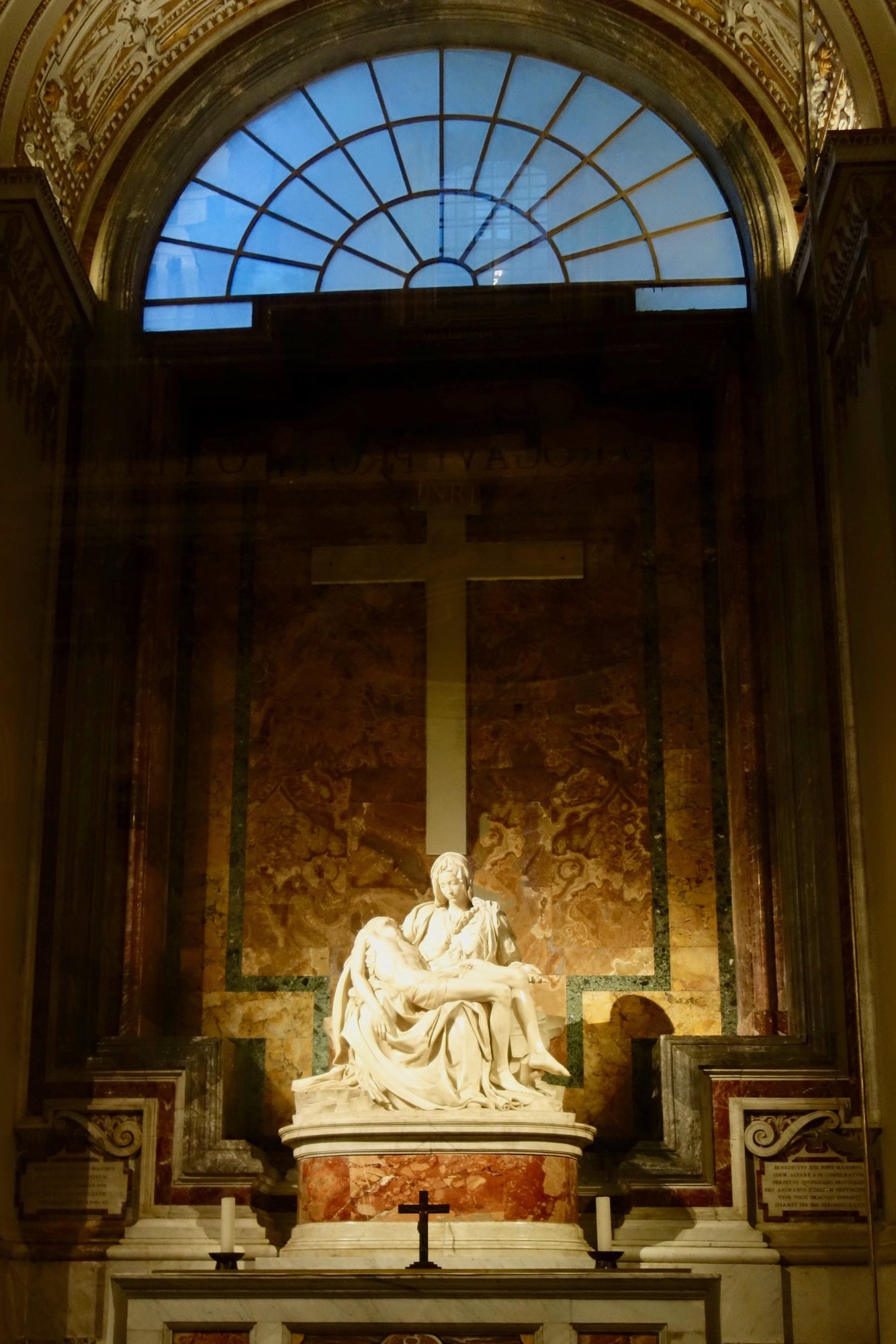 Detail of Michelangelo's Pietà showing the young face of the Virgin bent over the body of her son in quiet downward attention rather than overt grief.