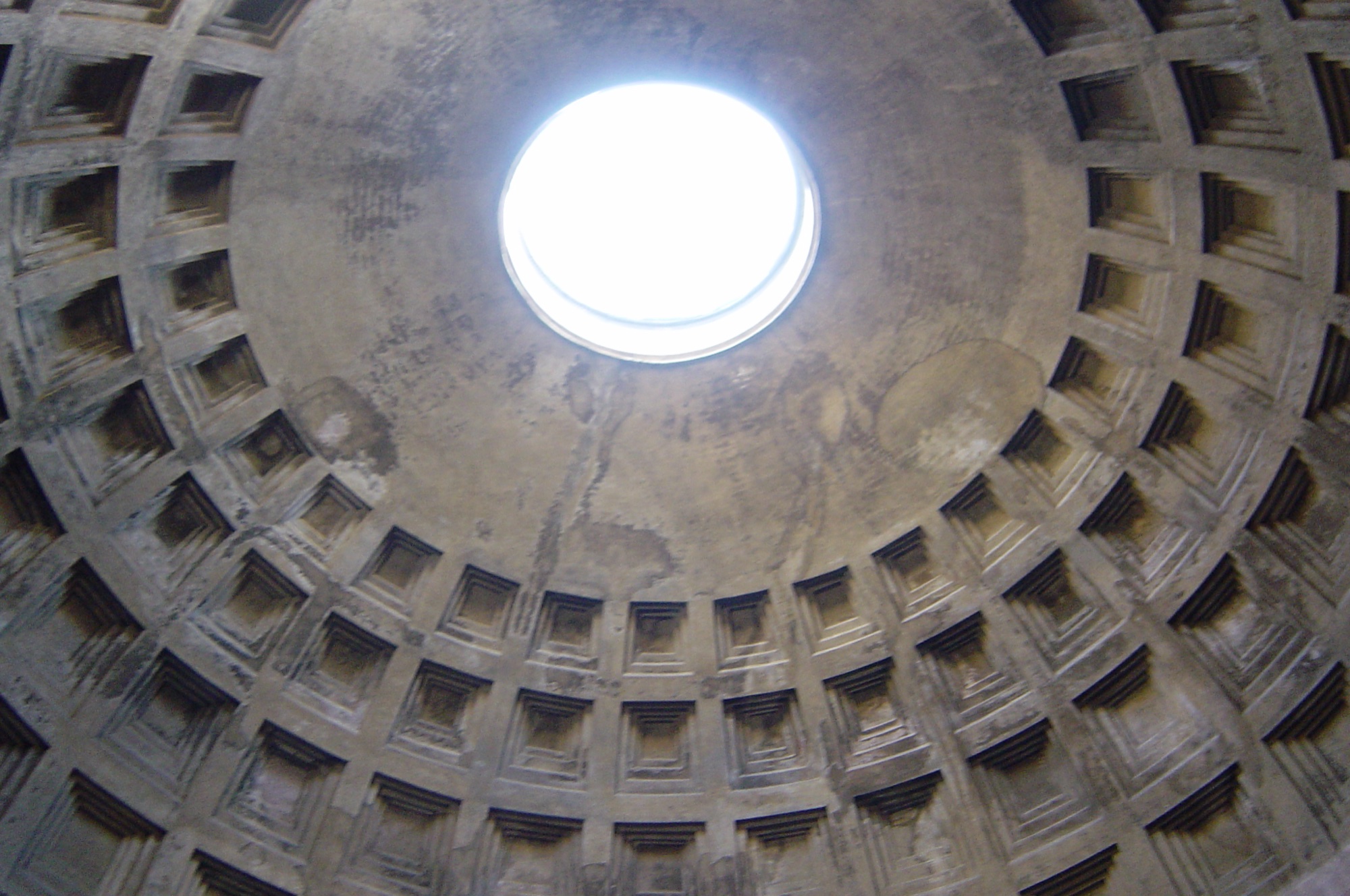 Looking up into the Pantheon's coffered concrete dome, with five concentric rings of recessed square panels narrowing toward the circular oculus open to the sky.