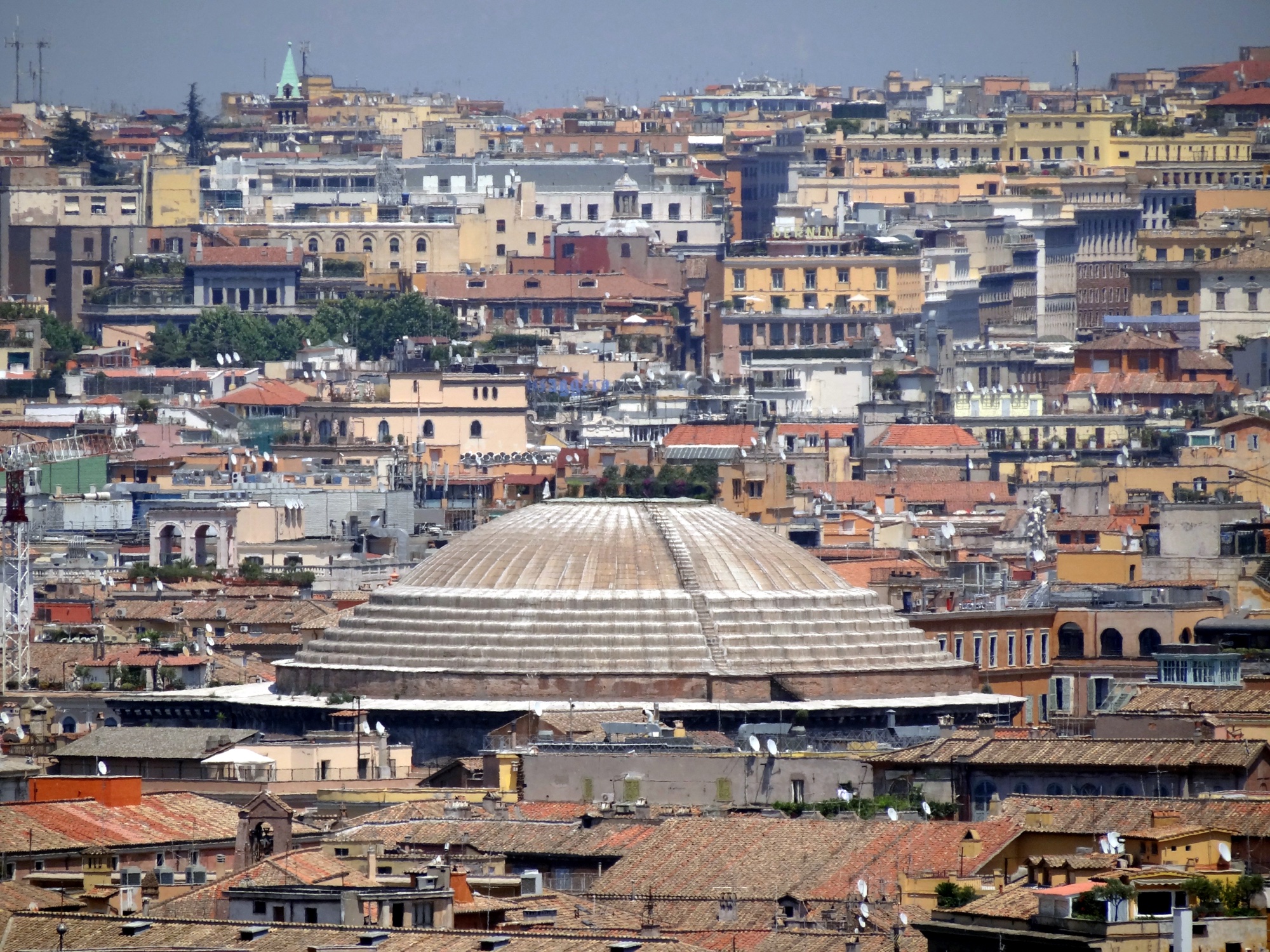 The dome of the Pantheon seen across the Roman rooftops from the Gianicolo hill, its shallow hemisphere rising unbuttressed above the city skyline.