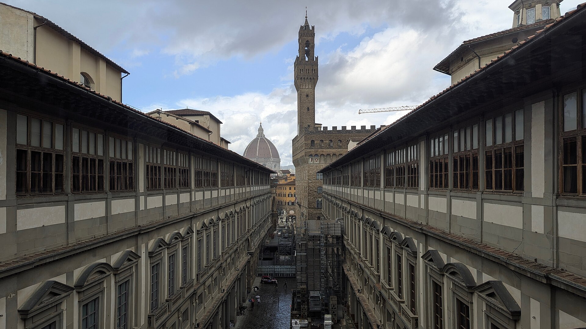 The Piazzale degli Uffizi from the river end of the courtyard, looking north toward Palazzo Vecchio's tower, with Vasari's two parallel wings running back toward the city. This is the courtyard you walk through to reach the entrance doors.